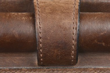 İki kahverengi deri kayış tutan deri kayış sahibinin detaylı bir yakın plan çekimi, gösterişli doku ve dikiş.