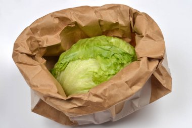 Bu kuş bakışı görüntü, buruşmuş kahverengi bir kesekağıdına yerleştirilmiş yeşil bir marul başlığını gösteriyor. Mutfak kullanımına hazır.