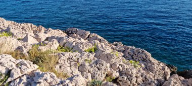 Krk adasındaki Kricin 'de güneşli, engebeli bir sahil. Keskin, kayalık arazi ile mavi denizin kesiştiği yer.