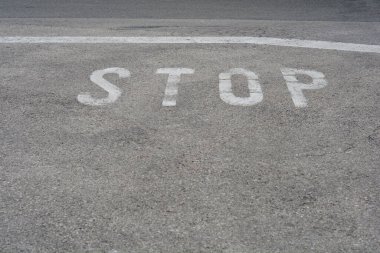 Gri asfalt bir yolda yıpranmış beyaz harflerle 