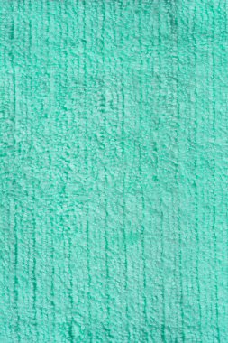 Açık yeşil bir mikrofiber kumaşın dikey yakın çekimi, kabarık bir dokusu var, temiz ve basit bir arkaplan görevi görüyor..