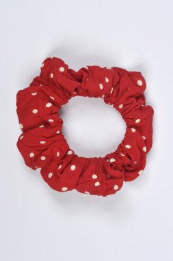 Beyaz benekli tek bir kırmızı kumaş tokası düz beyaz bir zemine serilmiştir.