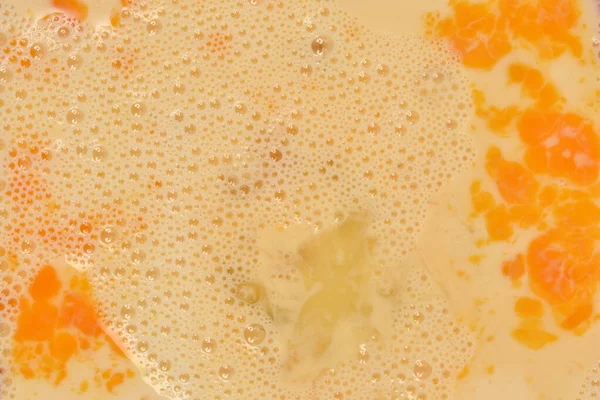 Görünür yumurta sarısı ve baloncuklu çırpılmış yumurtaların detaylı makro görüntüsü.