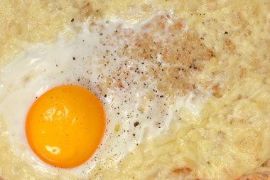 Eritilmiş peynirli kızarmış yumurta tostu ve karabiberli mükemmel pişmiş yumurta sarısı.