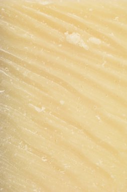 Parmesan peynirinin dokusunu ve kumlu yüzeyini vurgulayan yakın plan bir fotoğrafı.