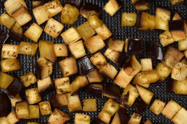 Makro, yakın plan, tepeden tırnağa kavrulmuş, doğranmış patlıcan, baharatla tatlandırılmış, lezzetli altın-kahverengi bir dokuya sahip