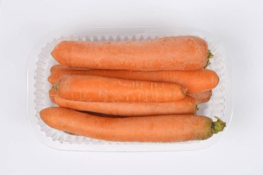 Temiz beyaz arka planda temiz, yıkanmamış havuçlu plastik bir kabın tepeden tırnağa görüntüsü