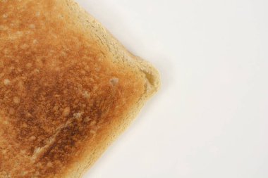 Beyaz seramik tabakta büyük bir kopya alanı olan mükemmel kızarmış altın-kahverengi bir ekmek diliminin yakın çekim görüntüsü.
