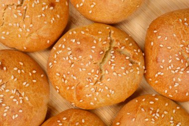 Bir grup taze, altın sarısı kahverengi ev yapımı susamlı çörekleri yakalıyor.