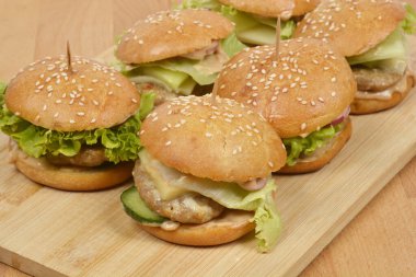 Bir grup ev yapımı susamlı hamburgerin düşük açılı, yakın plan çekimi. En yakındaki tahtanın üzerine odaklanmış.