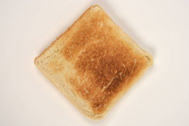 Beyaz seramik tabakta, mükemmel kızarmış, altın sarısı, kahverengi bir ekmek diliminin yukarıdan aşağıya yakın görüntüsü.