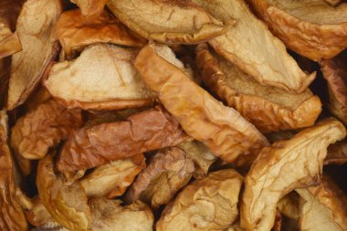 Kurumuş elmaların tam kare görüntüsü zengin dokusunu ve sıcak, kahverengimsi tonlarını gözler önüne serer.