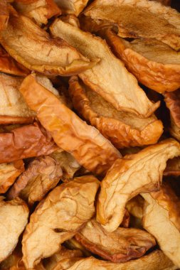 Kurumuş elmaların tam kare görüntüsü zengin dokusunu ve sıcak, kahverengimsi tonlarını gözler önüne serer.