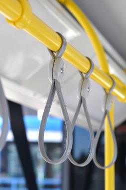 Kamu otobüsünde veya tramvayda duranlar için gri plastik kayışlı sarı tırabzanların yakın plan çekimi.
