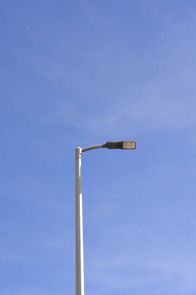 Минималистский вертикальный снимок одинокой уличной лампы на фоне ясного голубого неба