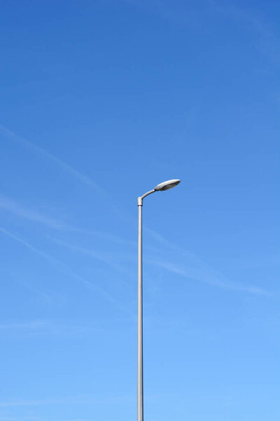 A minimalist vertical shot of a lone street lamp against a clear blue sky