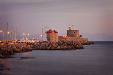 Yel değirmenleri ve liman iskelede güçlendirilmis deniz feneri. Rhodes town, Yunanistan.