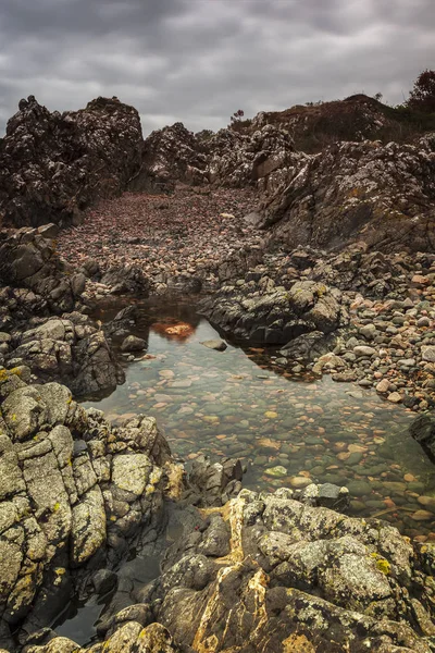 Natural cliffs and rocks by pool of water.