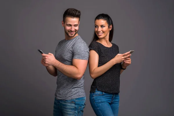Güzel Genç Bir Çift Arka Arkaya Ayakta Tutan Onların Smartphone — Stok fotoğraf