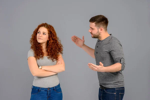 A beautiful young couple standing and arguing in the studio