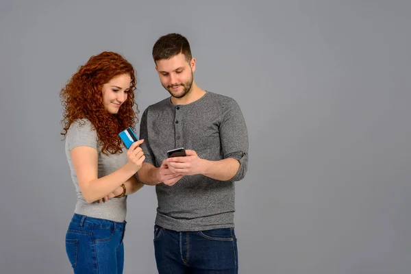 Hezký Mladý Muž Držící Smartphone Zatímco Jeho Přítelkyně Ukazuje Kreditní — Stock fotografie