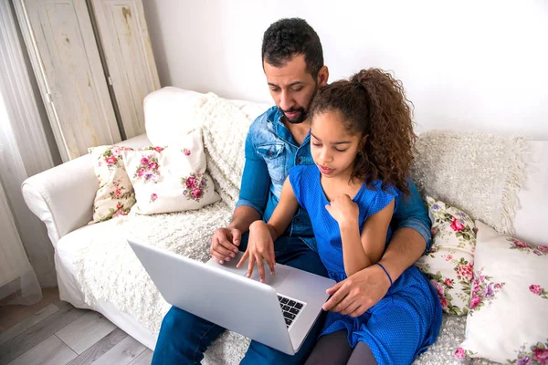 一个年轻的黑人父亲与他的女儿在沙发上 而他们正在使用笔记本电脑 — 图库照片