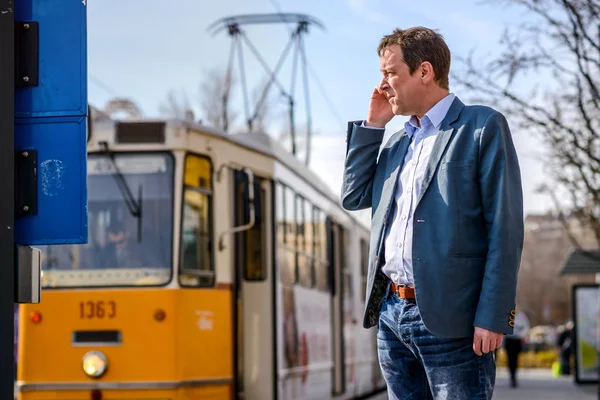 Medelålders Affärsman Står Och Väntar Spårvagnsstation Samtidigt Som Talar Hans — Stockfoto