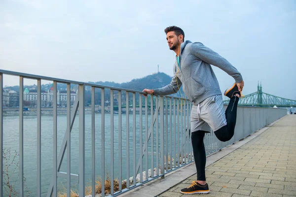 Een Knappe Jongeman Houden Van Het Hek Stretching Zijn Been — Stockfoto