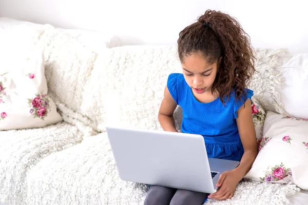 一个年轻的黑人少女坐在沙发上使用笔记本电脑 — 图库照片
