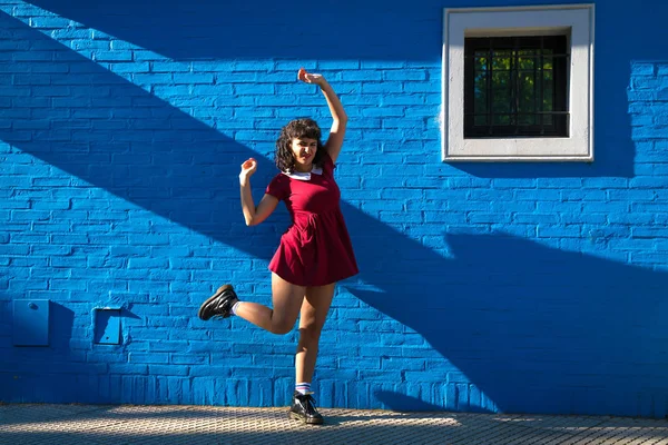 Una mujer con un vestido rojo posando frente a una pared — Foto de Stock