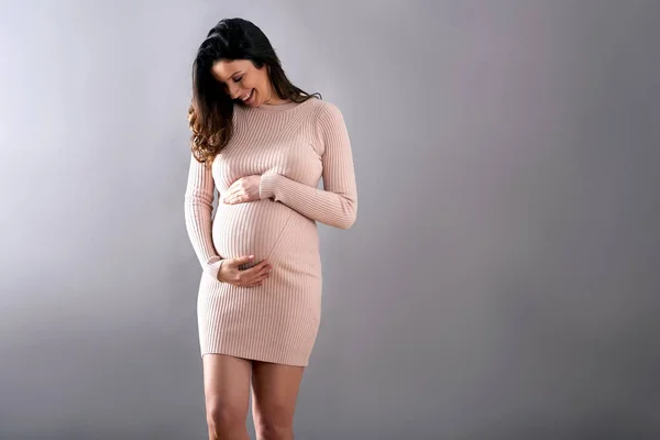 Uma mulher grávida elegante com as mãos na barriga — Fotografia de Stock