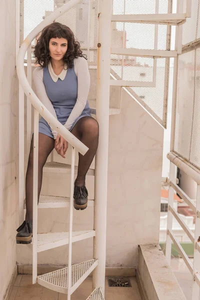 Una mujer sonriente con un vestido elegante sentada en las escaleras — Foto de Stock