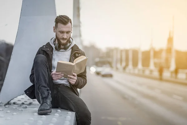 Photo de style rétro d'un hipster lisant sur un pont — Photo