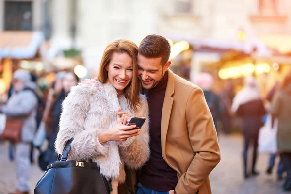 Пара перевіряє телефон на різдвяному ринку — стокове фото