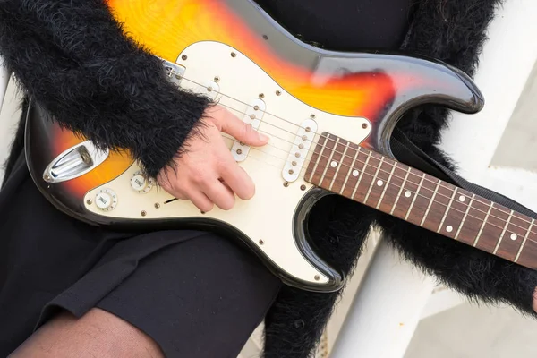 A woman in a black dress playing on a guitar — Stock Photo, Image