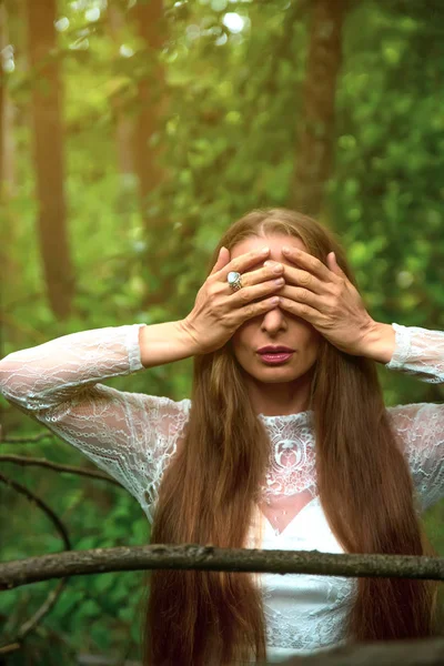 Una mujer en el bosque cubriéndose los ojos — Foto de Stock