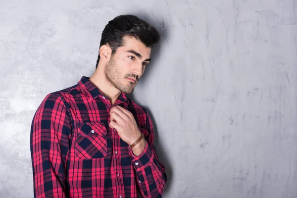 Un jeune homme sérieux dans une chemise à carreaux rouges — Photo