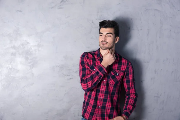 A thinking young man in a red checkered shirt — Stock Photo, Image