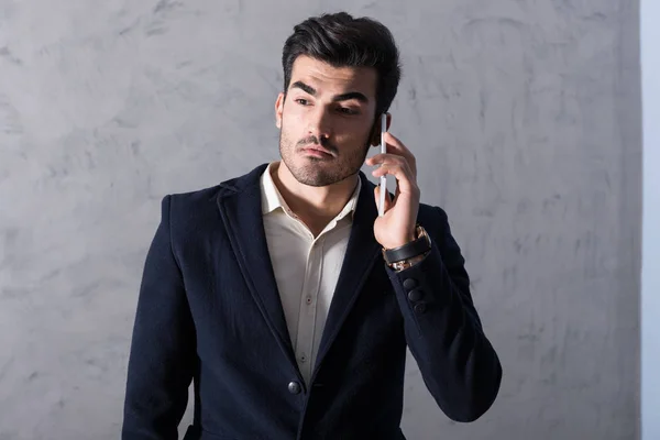 Серьезный молодой бизнесмен разговаривает по телефону в костюме — стоковое фото
