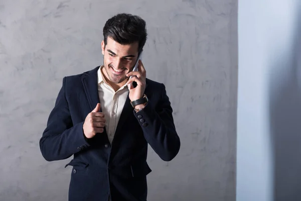Um jovem empresário feliz falando em seu telefone em um terno — Fotografia de Stock