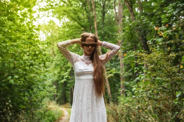 Una mujer en el bosque cubriéndose los ojos con su pelo — Foto de Stock