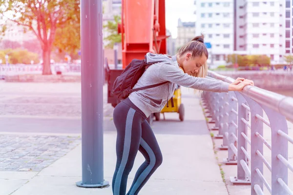 En atletisk kvinna vilar och lutar sig mot bron räcke — Stockfoto