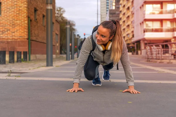 En atletisk kvinna stretching på gatan — Stockfoto