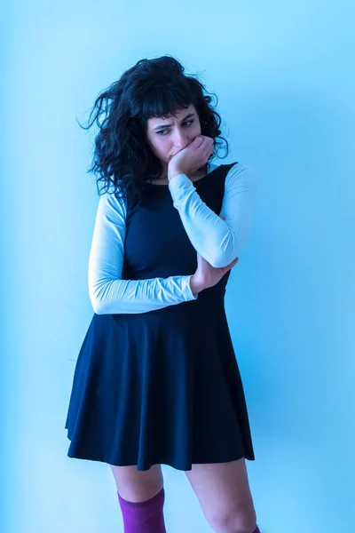 Une femme inquiète debout devant un mur blanc — Photo