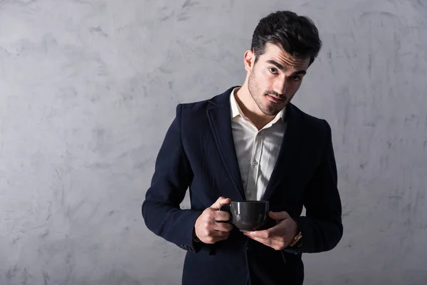 Un joven hombre de negocios serio en un traje con una taza — Foto de Stock