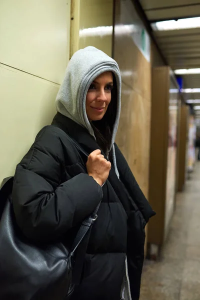 Uma jovem mulher sorridente de pé em uma estação de metrô — Fotografia de Stock