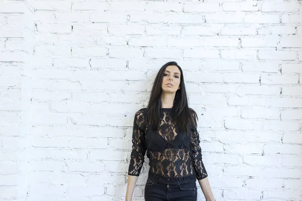 Una hermosa joven de pie frente a una pared blanca — Foto de Stock