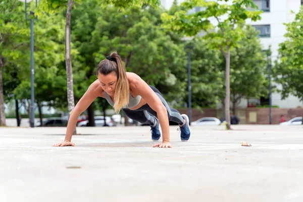 En atletisk kvinna göra push ups i parken — Stockfoto