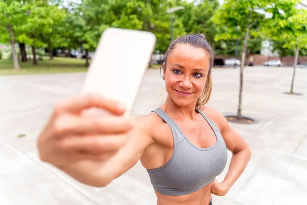 En atletisk kvinna som tar en selfie i parken — Stockfoto