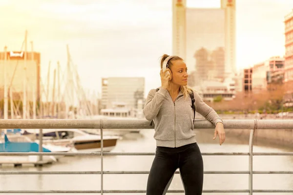 Una donna atletica che ascolta musica vicino alla ringhiera del ponte — Foto Stock